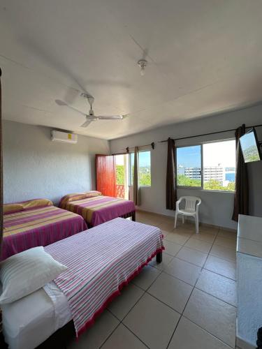 a hotel room with two beds and a window at Hotel Cabañas Pepe in Puerto Escondido