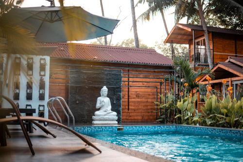 a pool with a statue of a buddha next to a house at Tranquill Riverside Luxury Cottages With Bathtub, Candolim in Candolim