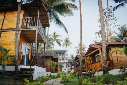 a row of houses on the beach with palm trees at Tranquill Riverside Luxury Cottages With Bathtub, Candolim in Candolim