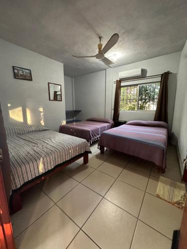 a bedroom with two beds and a window at Hotel Cabañas Pepe in Puerto Escondido