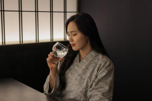 a woman sitting at a table drinking a glass of wine at Aank Ryokan Yosuriguri Cheonan in Cheonan
