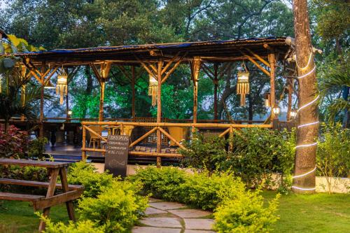 a wooden gazebo in a park with a bench at Tranquill Riverside Luxury Cottages With Bathtub, Candolim in Candolim