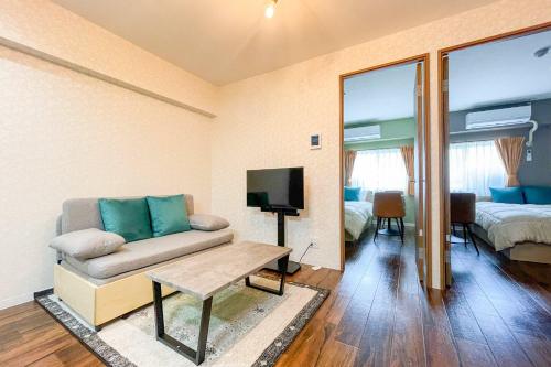 a living room with a couch and a tv and a bed at Alita Mansion Kyobashi in Osaka