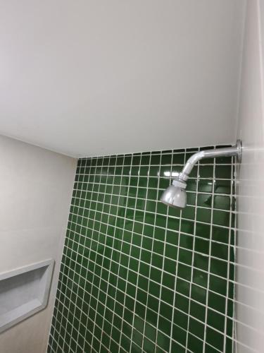 a shower with a green tiled wall with a shower head at Lev Apartments - Apto Beira-Mar - Posto 2 - Copacabana in Rio de Janeiro