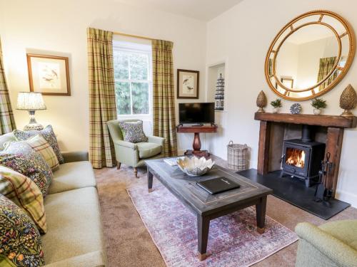 a living room with a fireplace and a mirror at Gate Lodge - Threave Estate in Castle Douglas