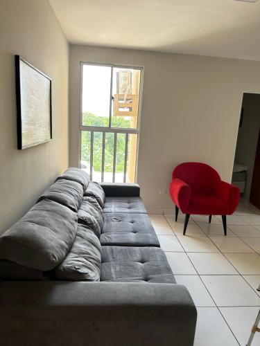 a living room with a couch and a red chair at Apartamento em Várzea Grande MT in Várzea Grande
