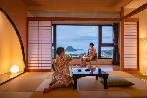 Kami Amakusa的住宿－Ooedo Onsen Monogatari Amakusa Hotel Kameya，两名妇女坐在一间享有海景的房间