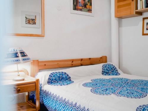 un lit avec des draps bleus et blancs et une lampe dans l'établissement Villa 2-pièces au calme avec mezzanine, terrasse et parking - 5 couchages - Animaux acceptés - FR-1-409-130, à Narbonne