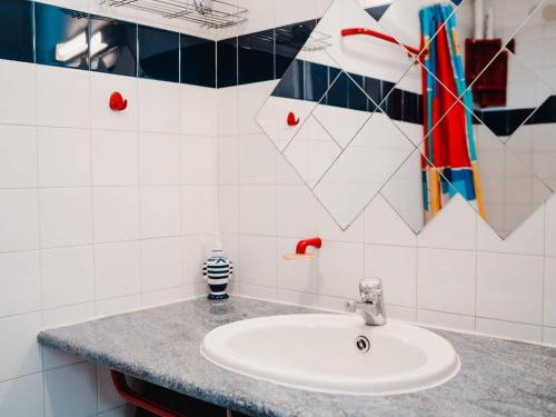 La salle de bains est pourvue d'un lavabo blanc et de carrelage coloré. dans l'établissement Villa 2-pièces au calme avec mezzanine, terrasse et parking - 5 couchages - Animaux acceptés - FR-1-409-130, à Narbonne