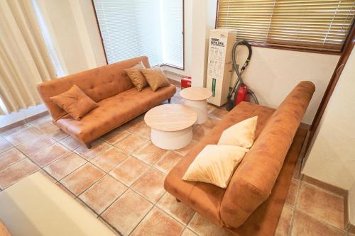 a living room with a brown couch and a table at FINOA Ikebukuro Sky Terrace Suite in Tokyo