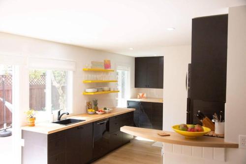 una cocina con armarios negros y un bol de fruta en la barra en Geometric Loft: renovated, hip, pets, pool/spa, en Solana Beach