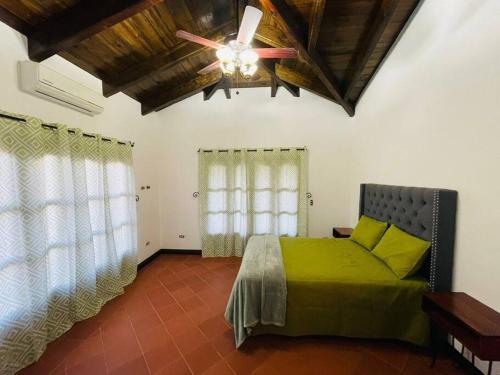 een slaapkamer met een groen bed en een plafondventilator bij Las guacamayas House in Copan Ruinas