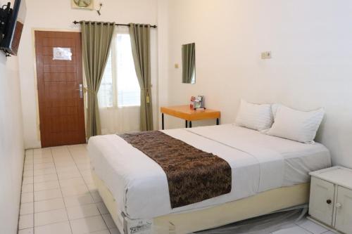 a bedroom with a large white bed with a window at Hotel Netral Jombang in Jombang