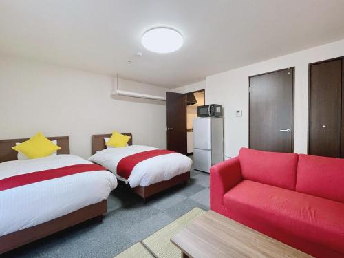 a hotel room with two beds and a red couch at Calm Stay Nijo in Kyoto