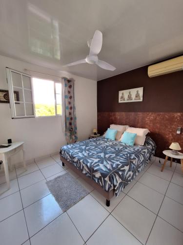 a bedroom with a bed and a ceiling fan at Villa Bois Rose in Petit-Bourg