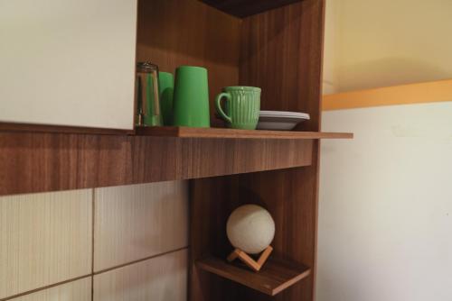 une étagère en bois avec des tasses vertes et un vase dessus dans l'établissement Pousada Salinas Valle, à Tramandaí