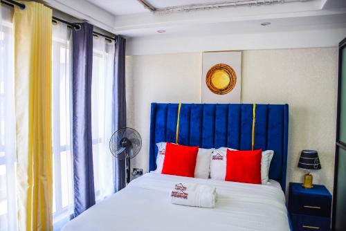 - une chambre avec une tête de lit bleue et un lit avec des oreillers rouges dans l'établissement Heartland Garden Kilimani, à Nairobi