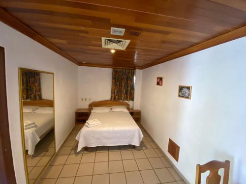 Cette petite chambre comprend un lit et un miroir. dans l'établissement GARDEN SUITES, à Aguascalientes