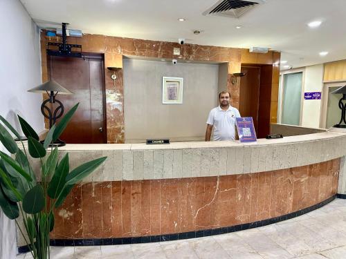 a man standing at a counter in a lobby at Swing & Pillows - Corona Inn Bukit Bintang in Kuala Lumpur