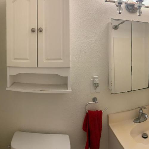 a bathroom with a toilet and a sink and a mirror at Nearby Beach House in El Segundo