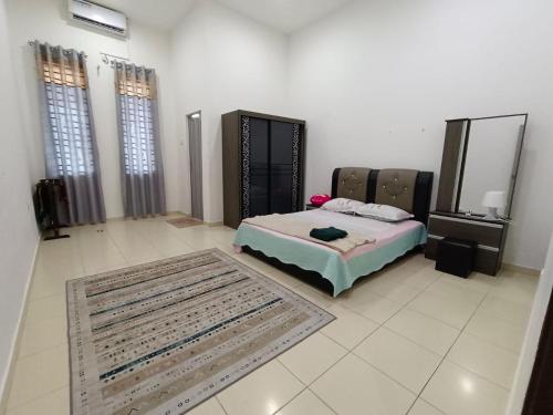 a bedroom with a bed and a rug and windows at Homestay Gua Musang in Gua Musang