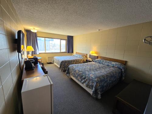 a hotel room with two beds and a television at Capri Motor Inn in Smithers