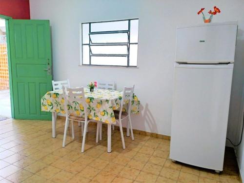Il comprend une cuisine équipée d'une table, de chaises et d'un réfrigérateur. dans l'établissement Casa Completa e Independente em Cabo Frio - RFV106, à Cabo Frio