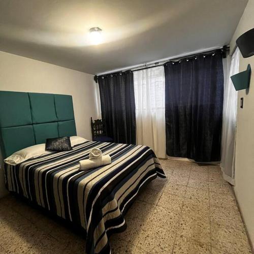 a bedroom with a bed with a striped blanket and a window at Hermoso departamento con Patio in Apizaco