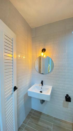 La salle de bains blanche est pourvue d'un lavabo et d'un miroir. dans l'établissement Grand Pool Villa Khonkaen เขื่อนอุบลรัตน์, 