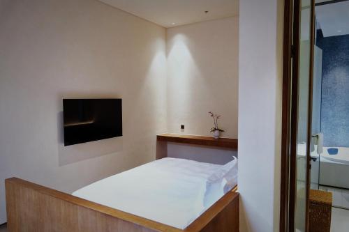 a bedroom with a bed and a tv on the wall at Glaze Garden Hotel in Yangzhou