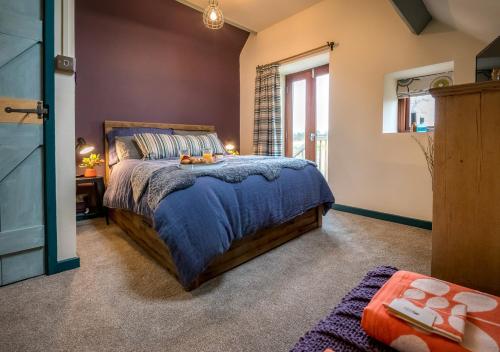 a bedroom with a bed with a blue comforter at Cysgu Llwynog in Llannor
