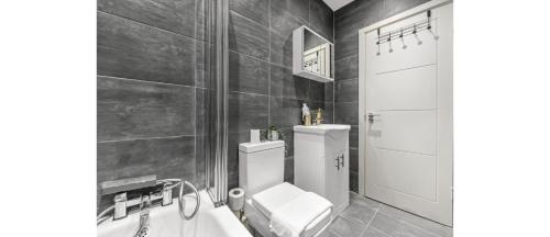 a bathroom with a toilet and a bath tub at City Elegance: Spacious 2BR for Urban Comfort in Twickenham