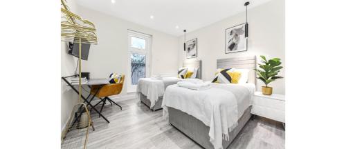 a bedroom with two beds and a desk in it at City Elegance: Spacious 2BR for Urban Comfort in Twickenham