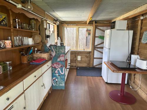 eine Küche mit einem weißen Kühlschrank und einem Tisch in der Unterkunft Casa Tavaita in Karangahake gorge in Paeroa