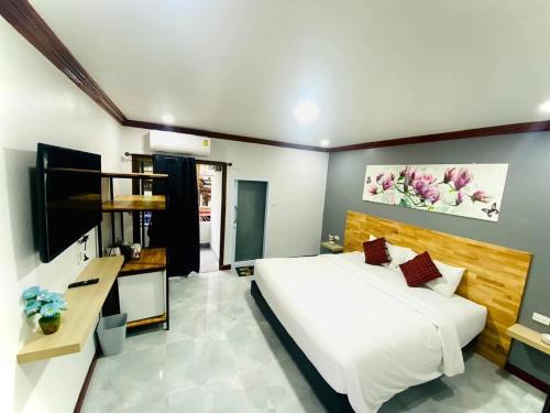 a bedroom with a large bed and a television at โรงแรมเอ็น.เจ. ธาตุพนม 