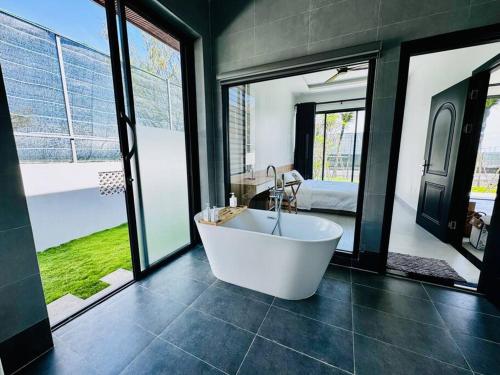 a large bathroom with a tub and a bedroom at Whispering waves beachfront villa in Tiến Thành