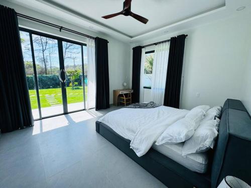 a bedroom with a large bed and a ceiling fan at Whispering waves beachfront villa in Tiến Thành