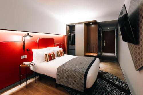 a hotel room with a bed and a red wall at Hotel Indigo Barcelona Plaza Espana by IHG in Barcelona