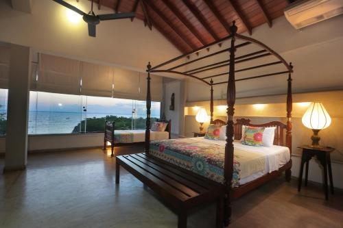 a bedroom with a canopy bed with a view of the ocean at Villa Hundira in Negombo