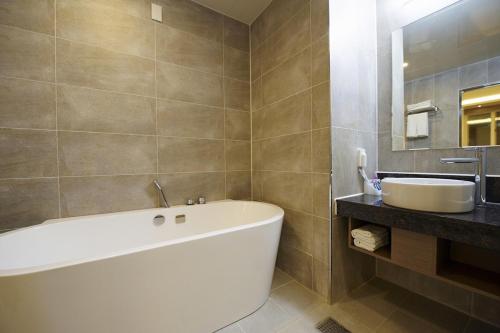 Hotel B في غوانغجو: حمام مع حوض أبيض ومغسلة