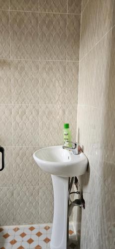 y baño con lavabo blanco y paredes de azulejos. en Kamili Homes - Apt 2, Morogoro, en Morogoro