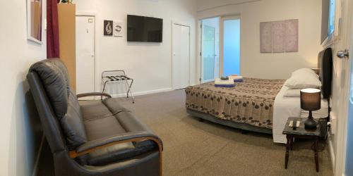 Gisborne Dream Suite في جيسبورن: غرفة نوم بسرير واريكة وكرسي