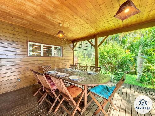a wooden deck with a table and chairs on it at Verger suspendu - avec piscine - 100m2 - Étang-Salé les Hauts in Gôl