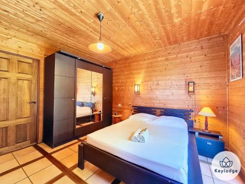 een slaapkamer met een bed in een houten kamer bij Verger suspendu - avec piscine - 100m2 - Étang-Salé les Hauts in Gôl