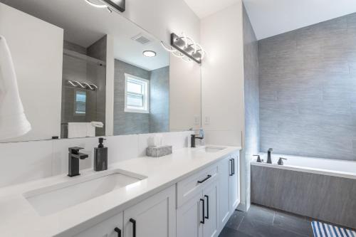 a white bathroom with two sinks and a bath tub at Room 1 of Lovely Montgomery Home, downtown Calgary in Calgary