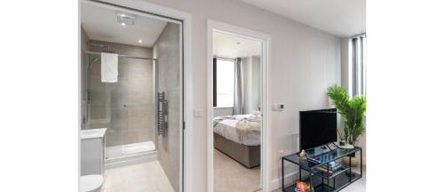 a bedroom with a bed and a bathroom with a mirror at Harmonious Greens: Cozy 1-Bed Flat in Harrow in Harrow
