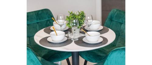 a white table with plates and glasses on it at Harmonious Greens: Cozy 1-Bed Flat in Harrow in Harrow