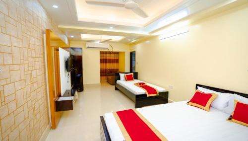 um quarto de hotel com duas camas e uma televisão em Adarsha Palace Hotel em Chuknagar