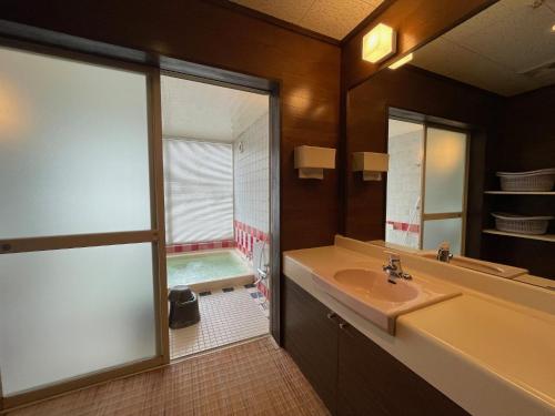 a bathroom with a tub and a sink and a mirror at マウンテンリゾート・マルガンタ Marganta in Madarao Kogen