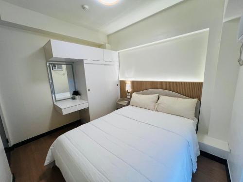 een kleine slaapkamer met een wit bed en een spiegel bij Estellar Resort Condotel in Manilla